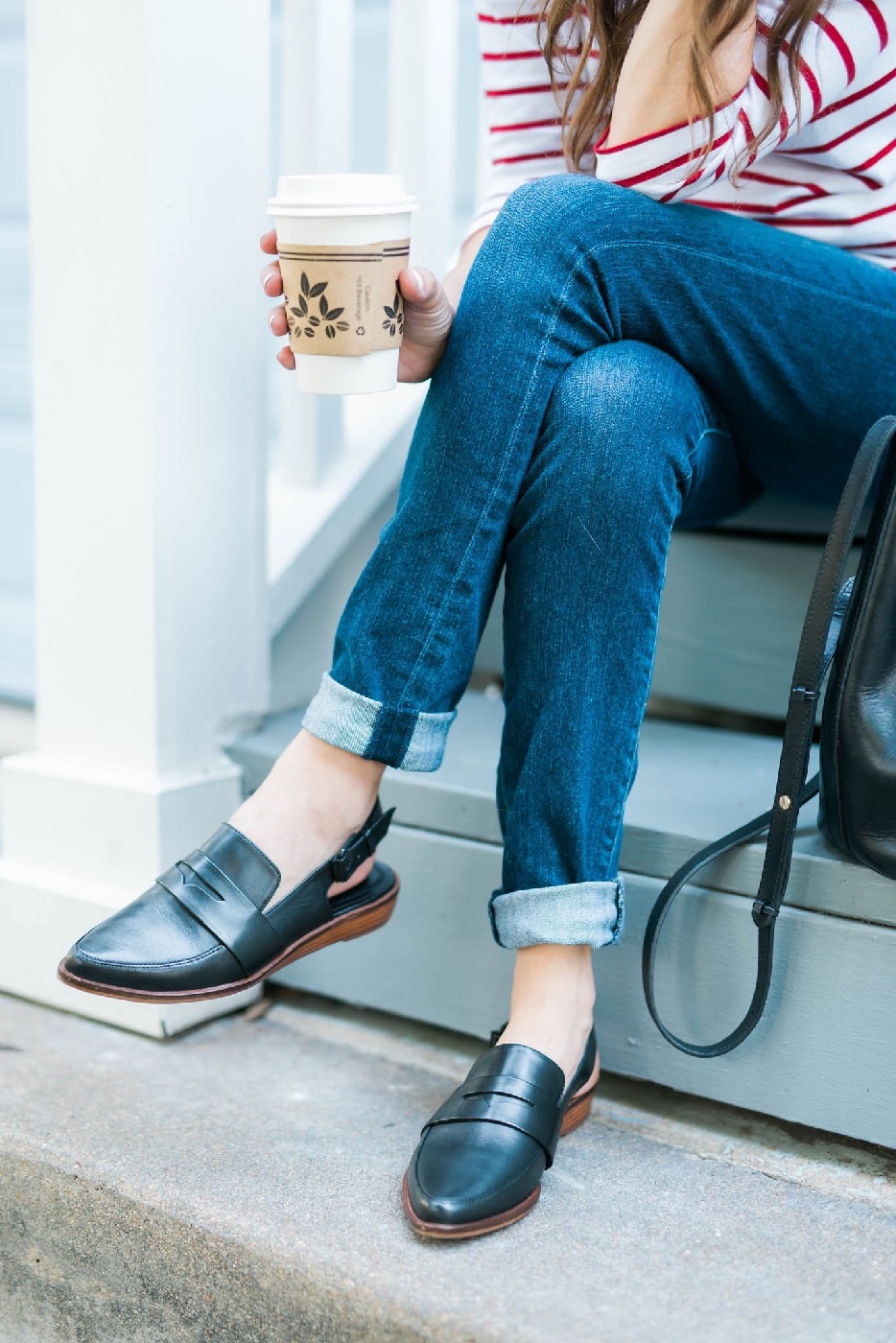 Wearing a pair of Kelsi Brooklyn Dagger black slip on loafers from Anthropologie with cuffed blue jeans.