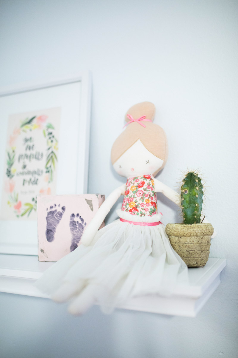 Baby girl nursery floating shelf with Anthropologie doll & succulent.