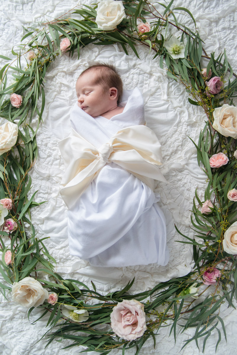 Newborn baby girl photography ideas: Beaufort bonnet bow swaddle in Palmetto Pearl and flower wreath.