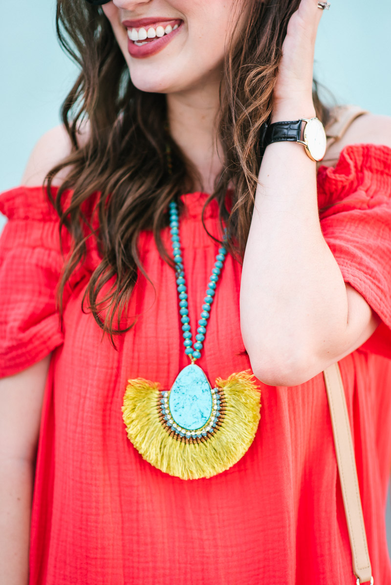 Red off the shoulder anthropolgoie dress styled with a turquoise fringe statement necklace.