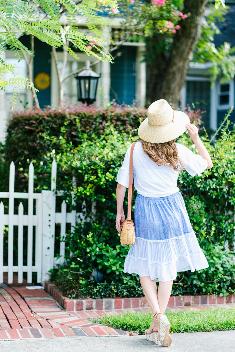 Anthropologie blue and white striped skirt paired with a white top and a straw sun hat.