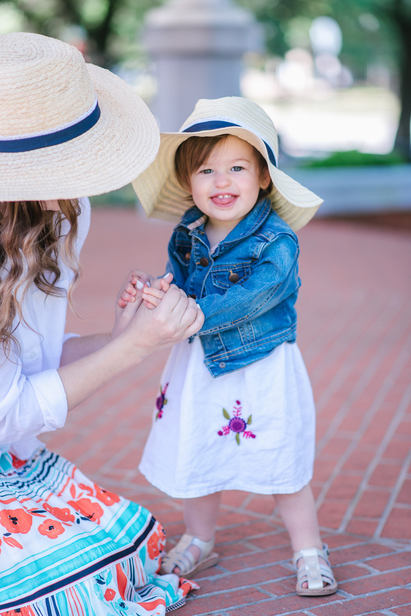 Toddler outfit in a straw hat with an embroidered dress and denim jacket.