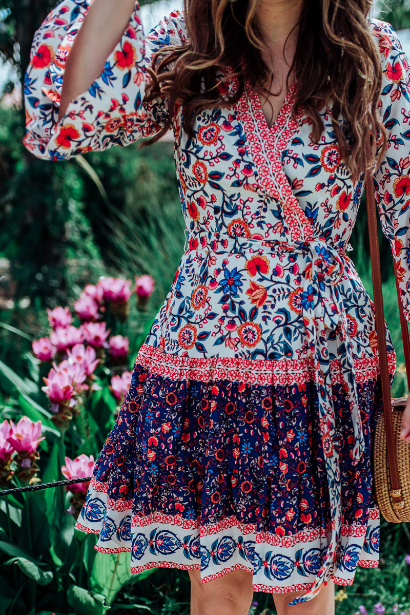 How to wear cowboy boots in the Summer featured by top US fashion blog, Lone Star Looking Glass: image of a woman wearing a floral Eliza J dress, Stree Level Crossbody bag, Daniel Wellington watch, Red Dress earrings and Tecovas cowboy boots for women