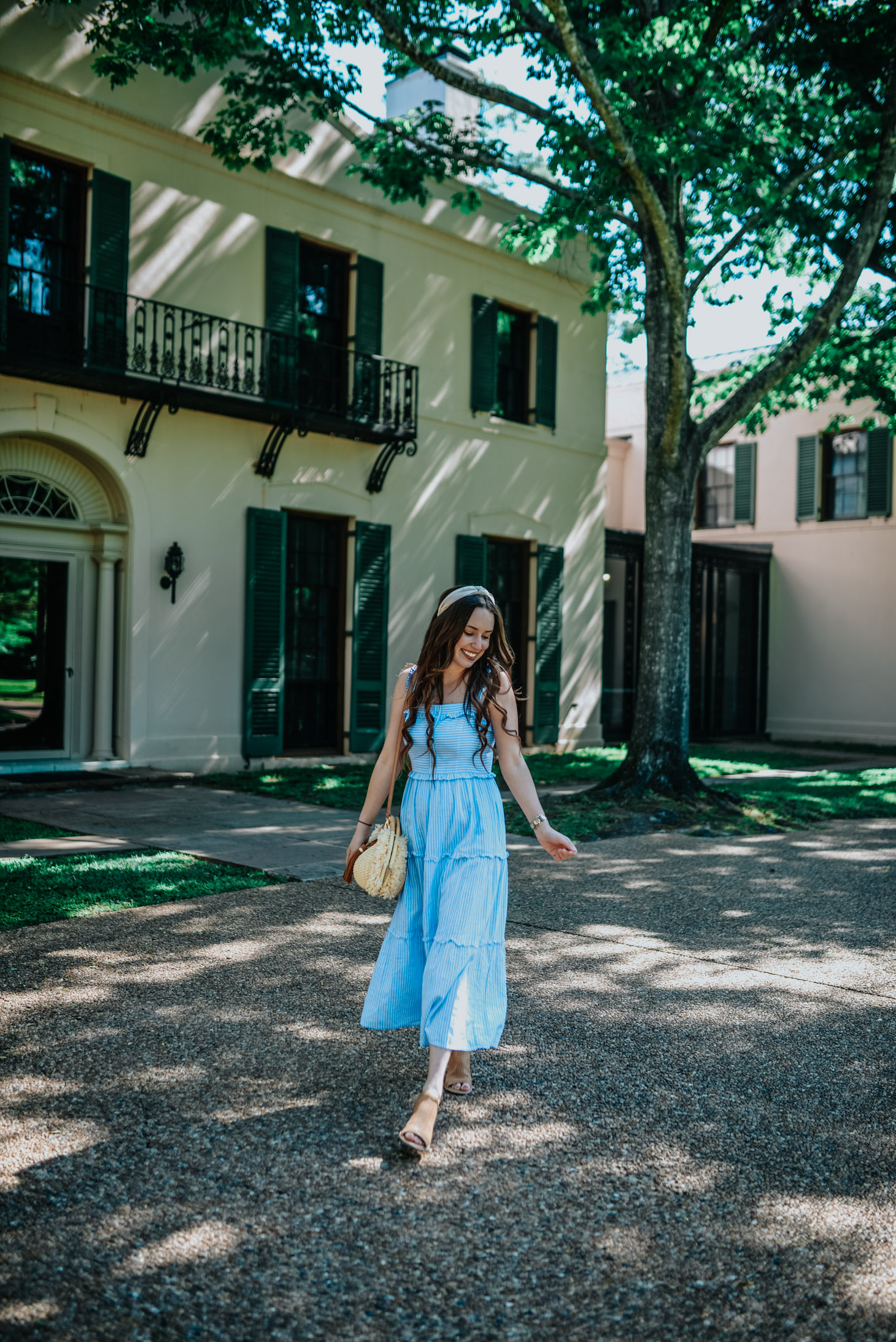 Visiting Bayou Bend Gardens in the Spring featured by top US travel and fashion blog, Lone Star Looking Glass: image of a woman walking through Bayou Bend Gardens wearing a Gal Meet Glam maxi dress, Anthropologie rafia headband and Sofft sandals