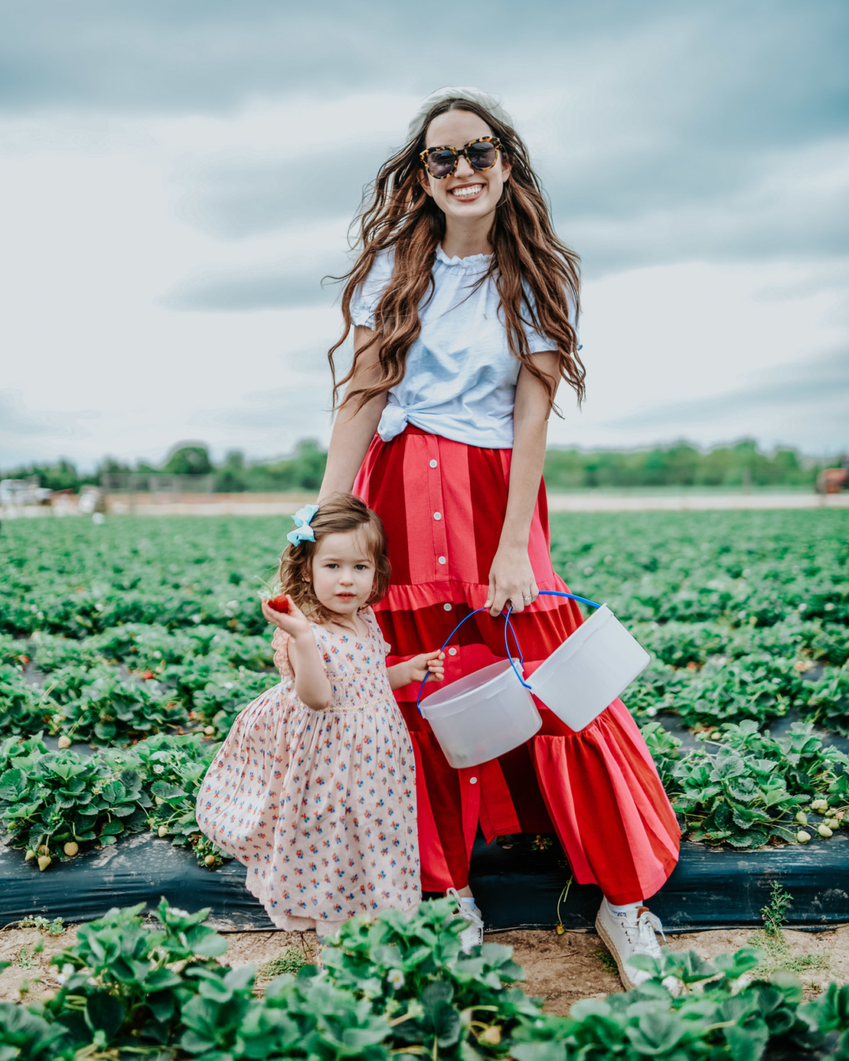 Where to Go Strawberry Picking in Houston: a review of strawberry picking at Froberg’s Farms featured by top US travel blog, Lone Star Looking Glass: image of a woman wearing a Rent the Runway colorblock maxi skirt, Anthropologie top and headband, Tretorn espadrille sneakers and her little girl