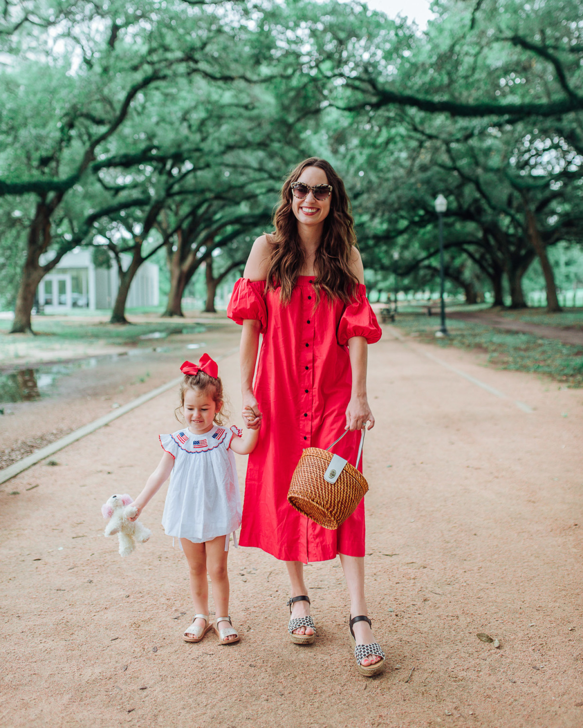 Mommy and Me 4th of July Outfits featured by top US fashion blog, Lone Star Looking Glass: image of a woman wearing an SWF boutique red off the shoulder dress, Francesca’s espadrille wedges and a Patricia Nash basket satchel and a toddler girl wearing a Cecil and Lou patriotic dress and Freshly Picked sandals.