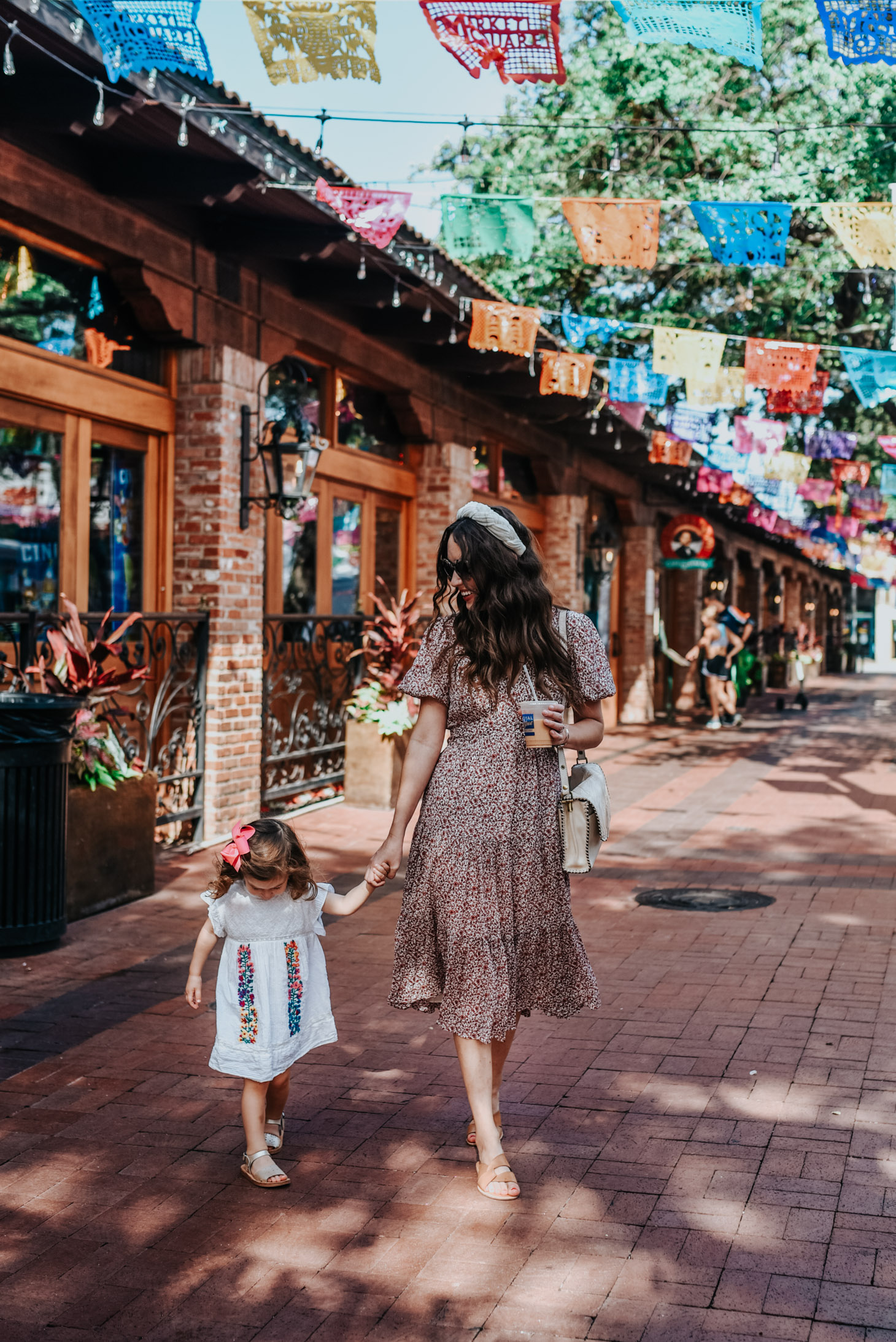 Top 10 Kid Friendly Activities in San Antonio by popular Texas travel blog, Lone Star Looking Glass: image of a a mom and her 2 year old daughter holding hands as they walk through the Historic Market Square in San Antonio, Texas.