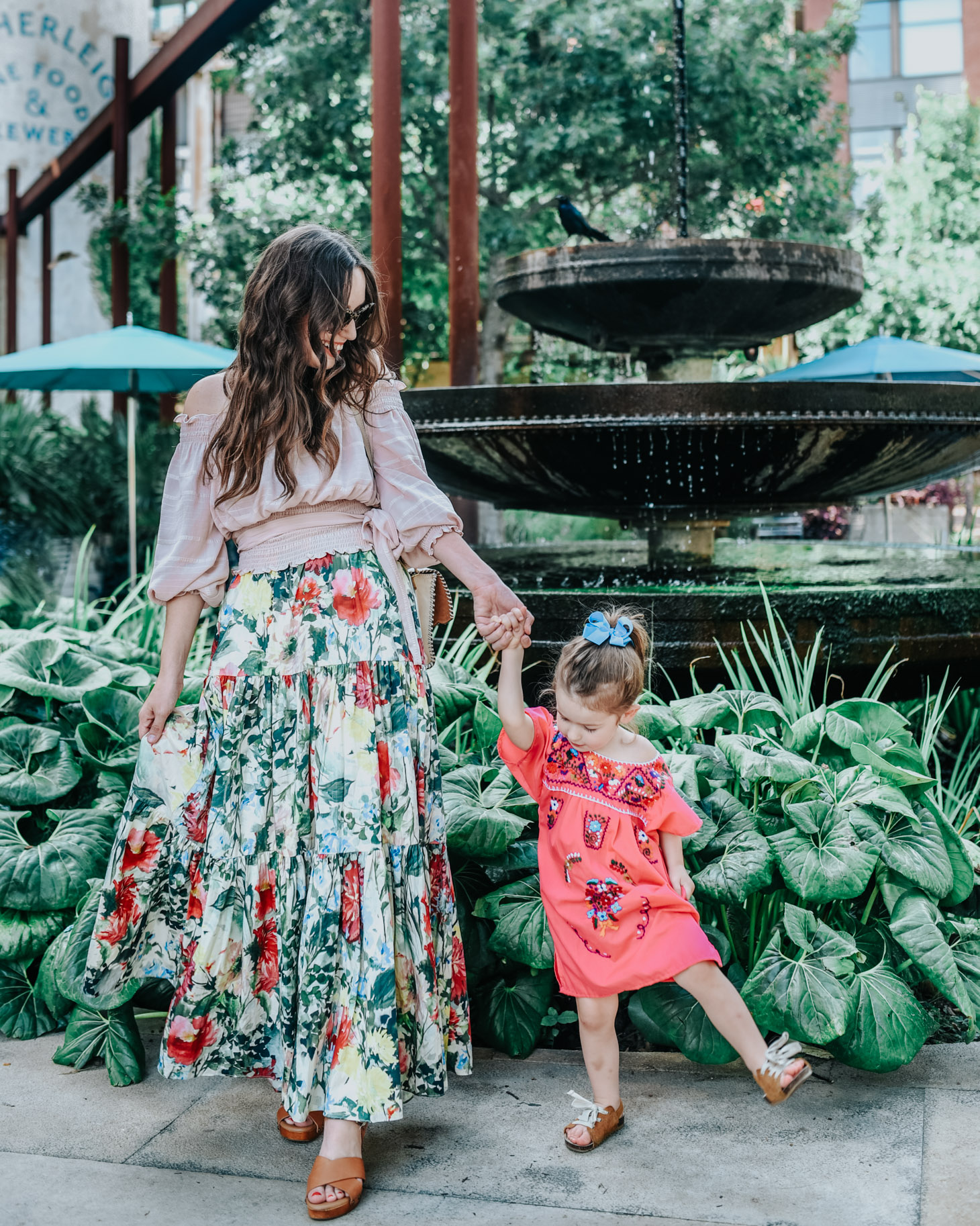 Top 10 Kid Friendly Activities in San Antonio by popular Texas travel blog, Lone Star Looking Glass: image of a mom and her daughter holding hands and standing in front of a large water fountain.