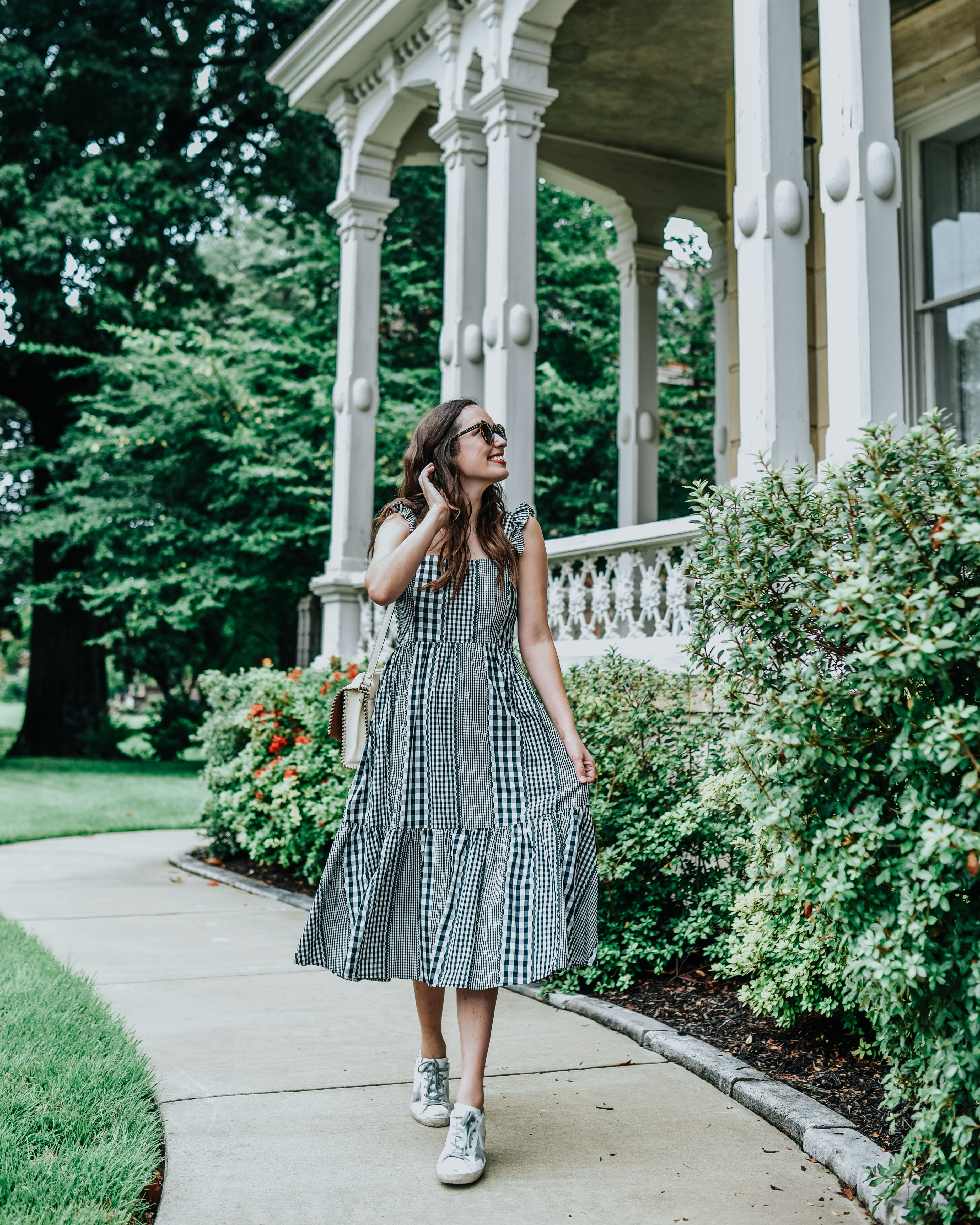5 Dress Designers to Take Note Of this Summer by popular Memphis fashion blog, Lone Star Looking Glass: image of a woman standing outside by a historic building and wearing a black and white gingham Crosby by Mollie Burch dress.