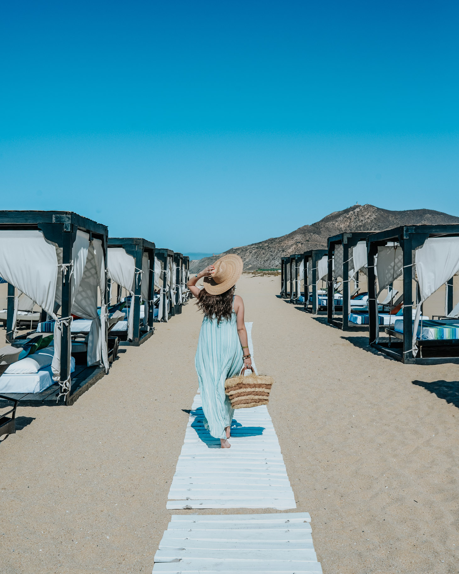 Pueblo Bonito Pacifica: 8 Reasons to Vacation in Cabo by popular Tennessee travel blog, Lone Star Looking Glass: image of a woman walking by beach cabanas at the Pueblo Bonito Pacifica.