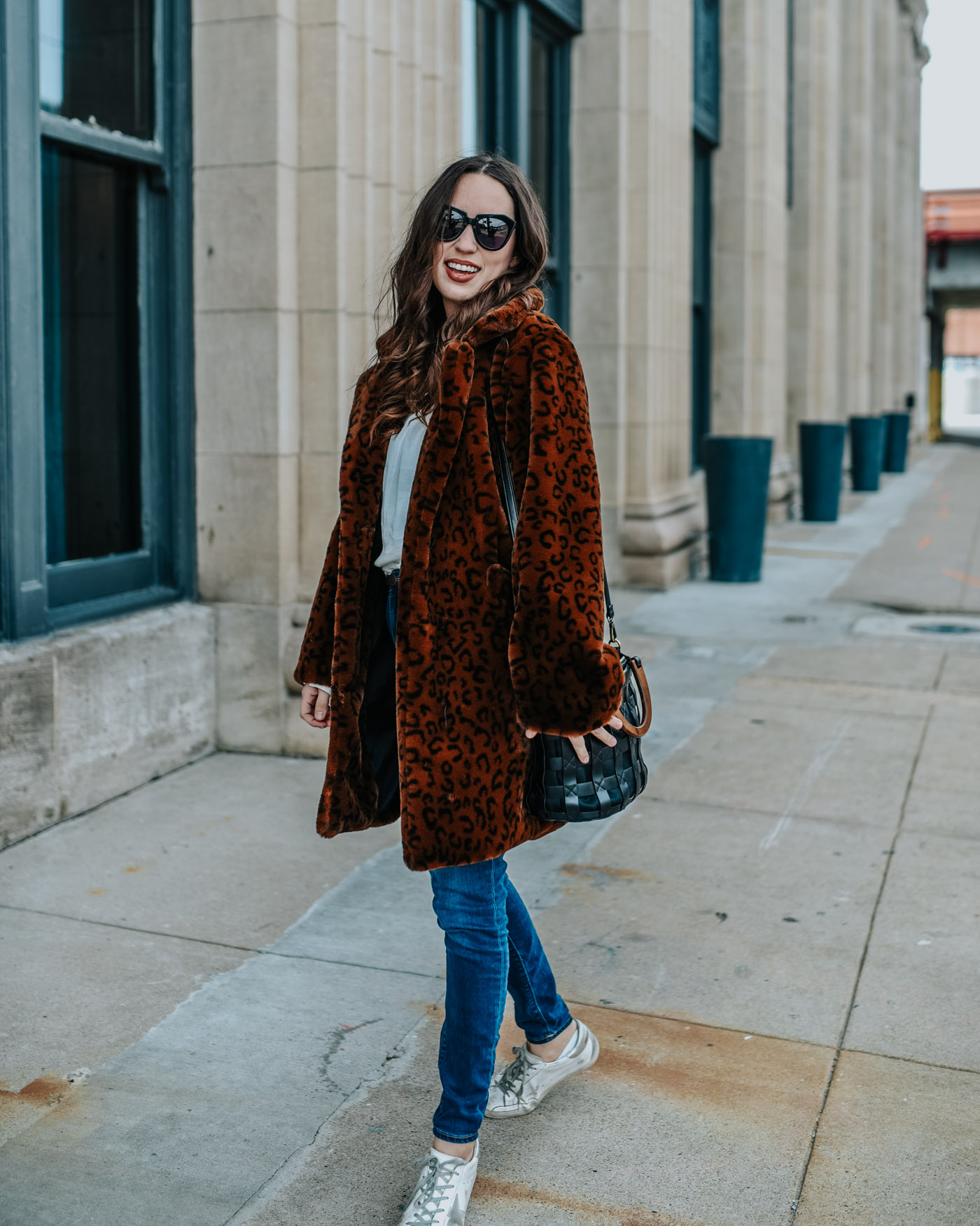 Luxe leopard coat styled down by top US fashion blog, Lone Star Looking Glass: image of a woman wearing a Revolve luxe leopard coat, Golden Goose sneakers and skinny jeans.