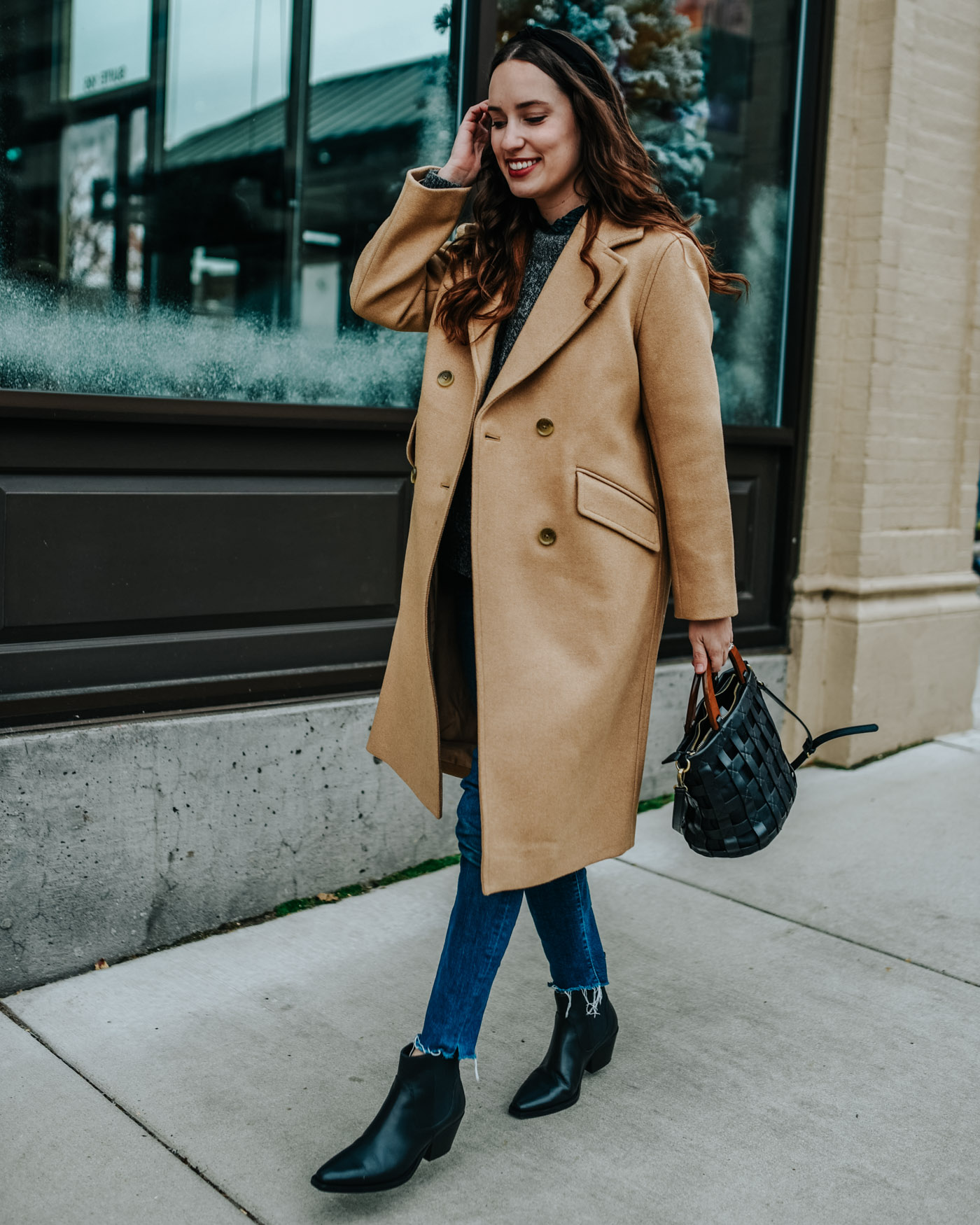 My 5 Wardrobe Winter Essentials by popular Tennessee fashion blog, Lone Star Looking Glass: image of a woman walking outside in a city and wearing a pair of Everlane The Western Boot, Everlane The Oversized Alpaca Crew, black knotted headband and Everlane The Italian ReWool Overcoat.