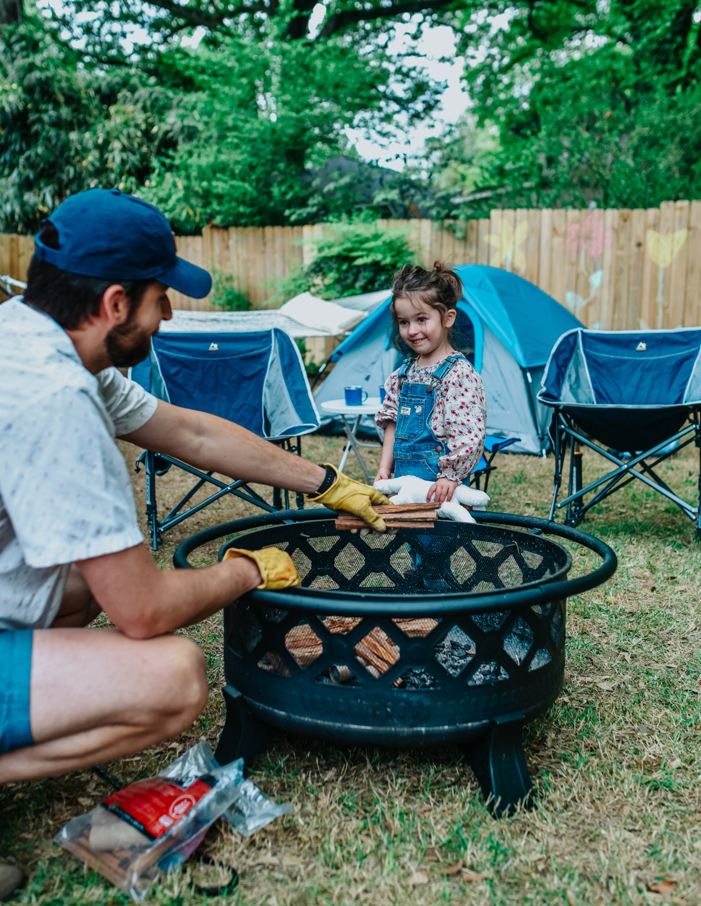 Backyard Camping by popular Memphis lifestyle blog, Lone Star Looking Glass: image of a dad building a fire in a Academy Academy Mosaic 29 in Drew Deep Bowl Fire Pit with his daughter.