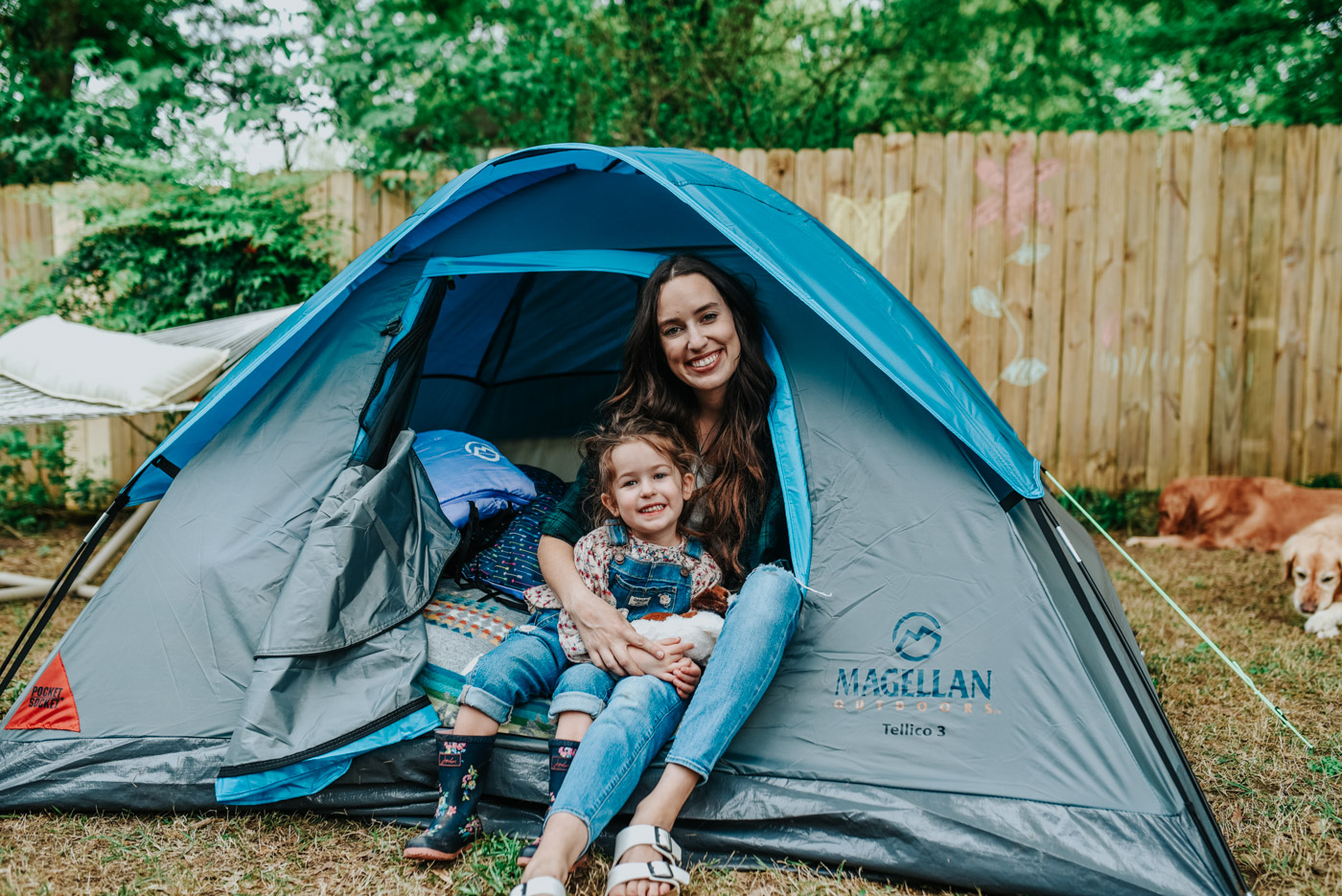 Backyard Camping by popular Memphis lifestyle blog, Lone Star Looking Glass: image of a mom wearing a Academy BCG Women's Slub Solid T-shirt and Academy Carhartt Women's Rugged Flex Hamilton Flannel Work Shirt and sitting with her daughter in a Academy Magellan Outdoors Tellico 3 Person Dome Tent with a Academy Queen-Size Plush Top Airbed and Academy Magellan Outdoors Kids' 45-Degree F Rectangular Sleeping Bag inside.