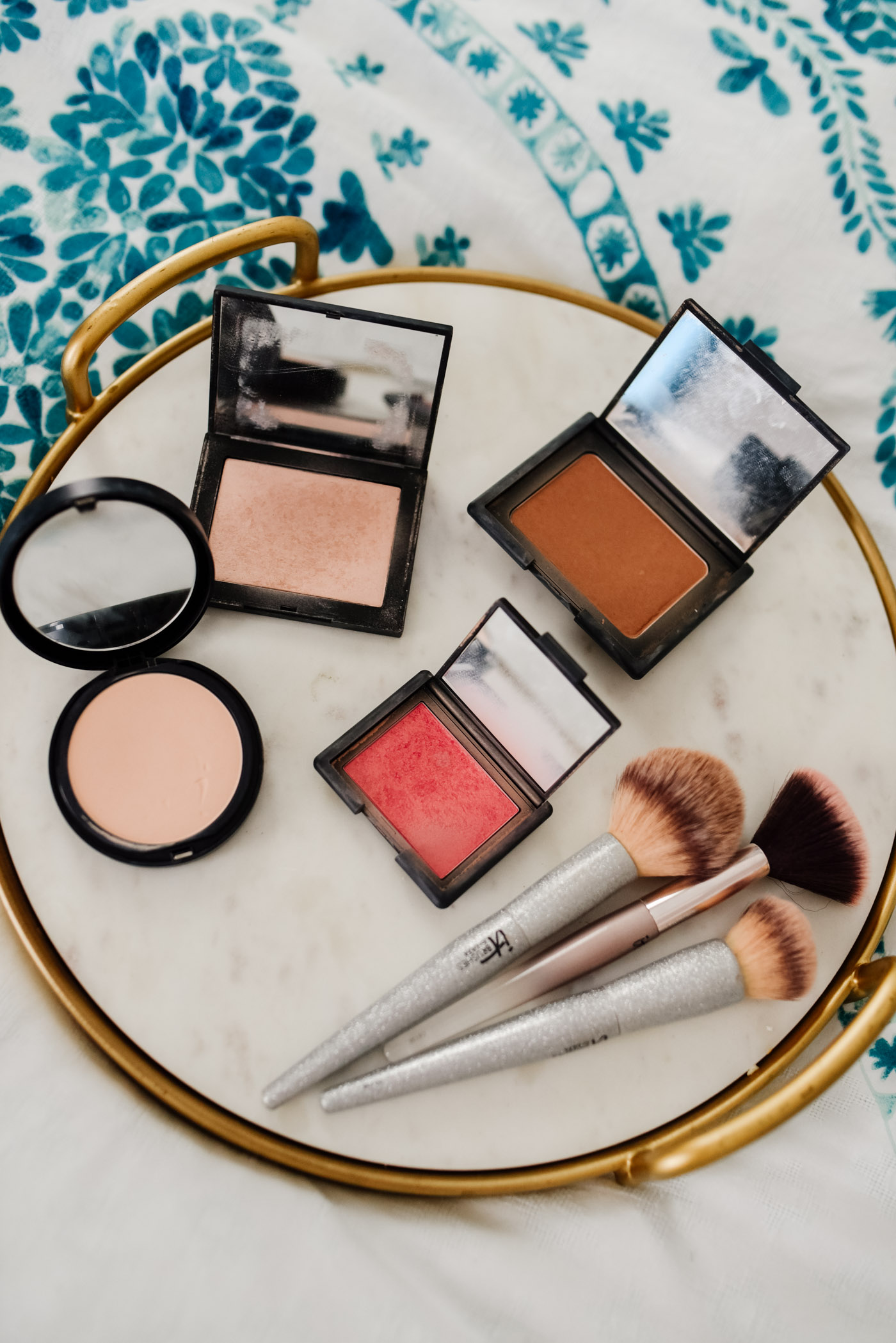 Morning Skin Care Routine by popular Memphis beauty blog, Lone Star Looking Glass: image of Nars blush, Nars bronzer, Bare Minerals setting powder and IT cosmetics brushes on a marble and gold tray. 