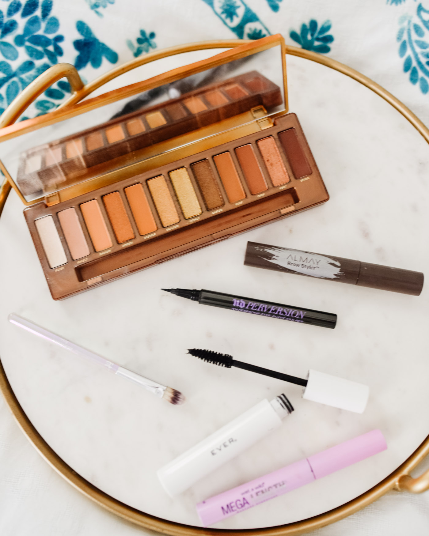 Morning Skin Care Routine by popular Memphis beauty blog, Lone Star Looking Glass: image of Urban Decay naked pallet, Urban Decay perversion liquid eyeliner, Alamay brow styler, Ever's Whiplash mascara, and Wet n' Wild Mega mascara on a marble and gold tray. 