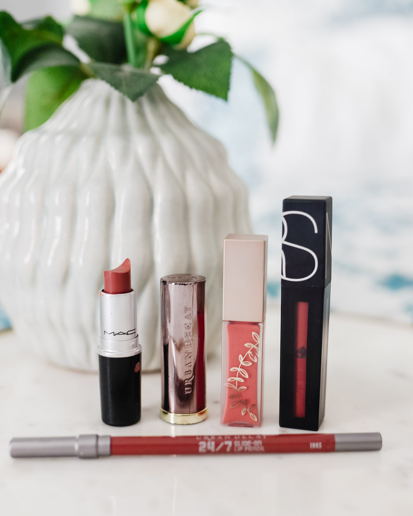 Morning Skin Care Routine by popular Memphis beauty blog, Lone Star Looking Glass: image of MAC lipstick, Urban Decay lipstick, Urban Decay 24/7 glide on lip pencil, and Nars powermatte lip pigment next to a white flower vase.  