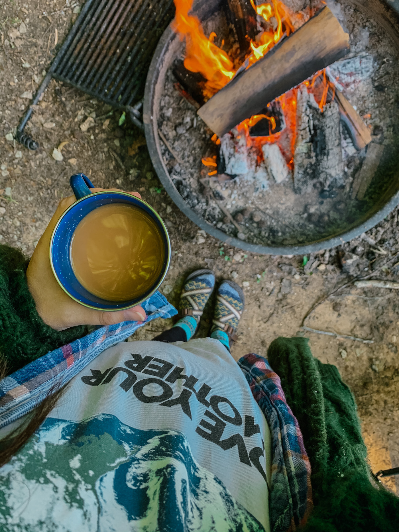 Father's Day Gift Ideas by popular Memphis lifestyle blog, Lone Star Looking Glass: image of a woman holding a blue enamel mug filled with coffee next to a camp fire. 