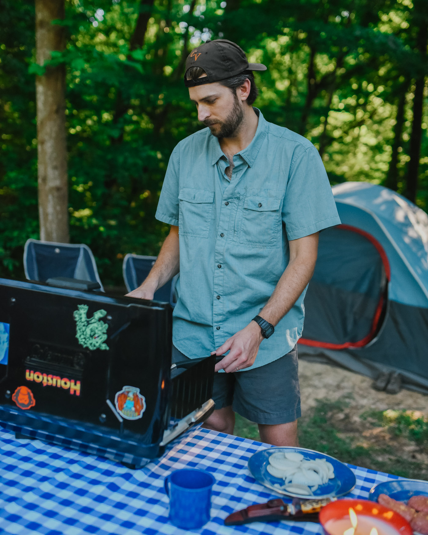 Father's Day Gift Ideas by popular Memphis lifestyle blog, Lone Star Looking Glass: image of a man wearing a Academy Sports Magellan Outdoors Men's Button Down shirt and cooking on a Coleman PerfectFlow 2 Burner Camp Stove. 