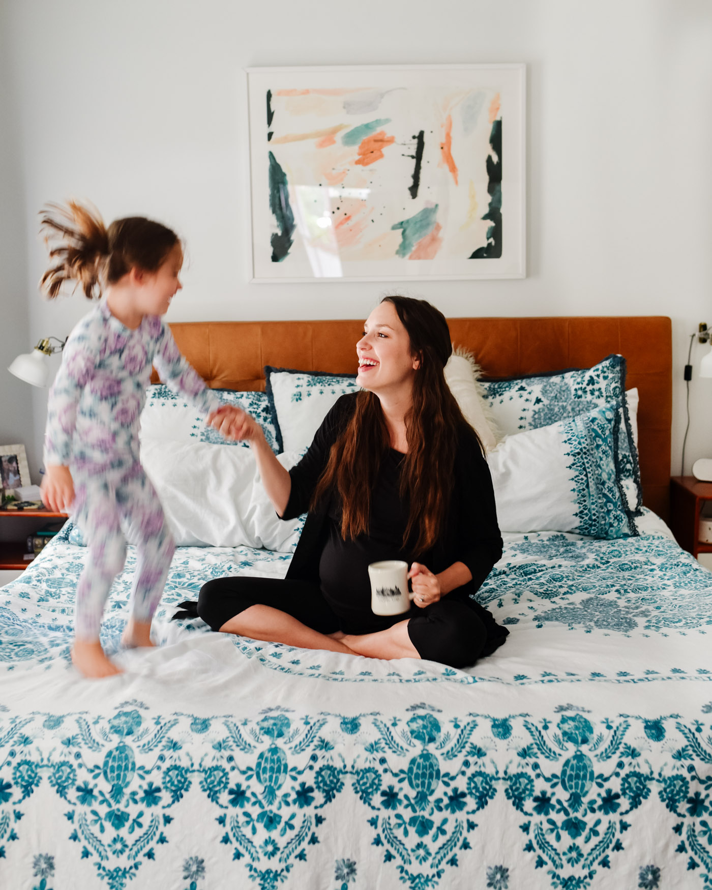 Maternity Pajamas by popular Memphis fashion blog, Lone Star Looking Glass: image of a woman sitting on her bed while holding a coffee mug and wearing a Kindread Bravely Emmaline Robe. 