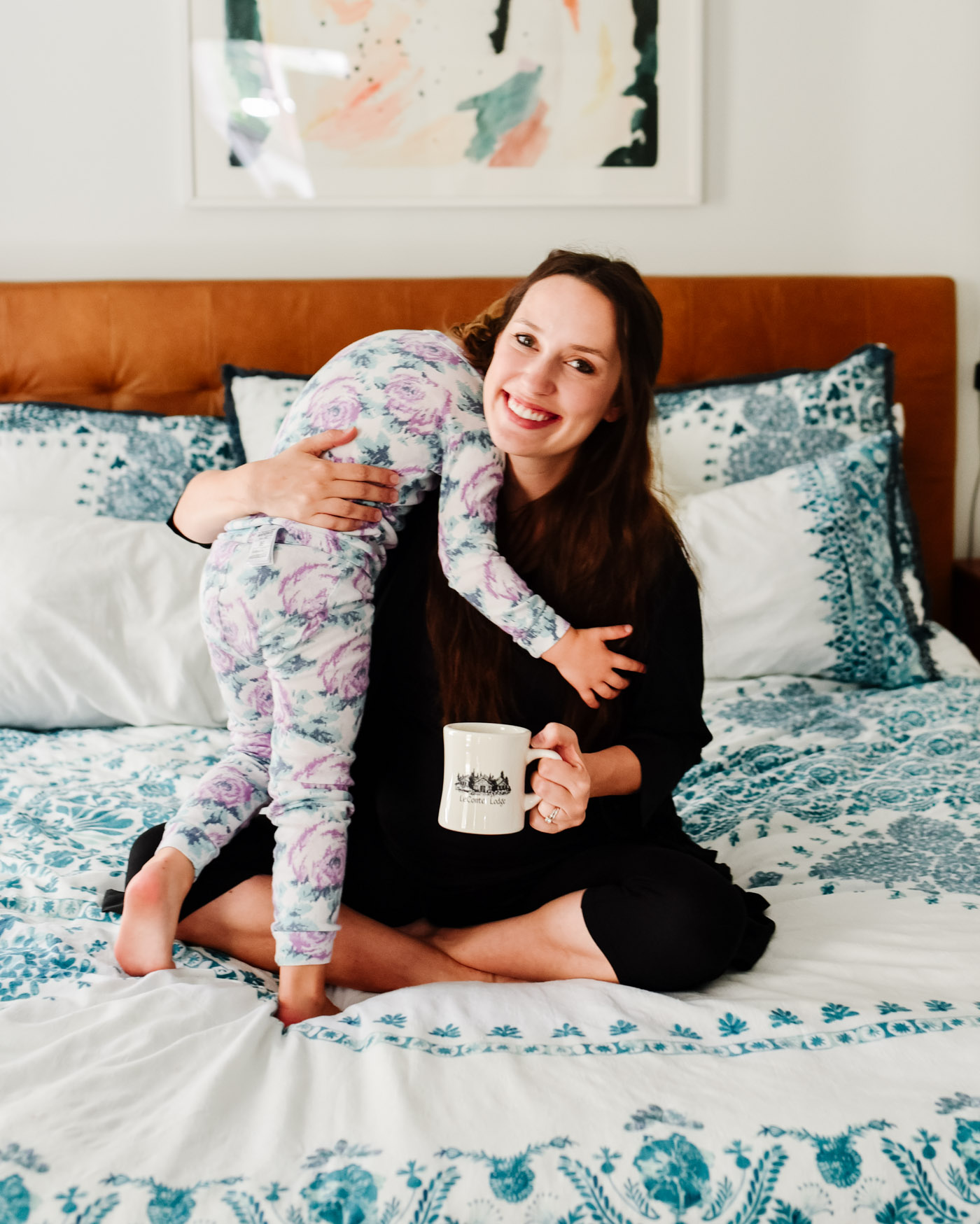 Maternity Pajamas by popular Memphis fashion blog, Lone Star Looking Glass: image of a woman sitting on her bed and holding her young daughter while wearing a Kindread Bravely Emmaline Robe. 