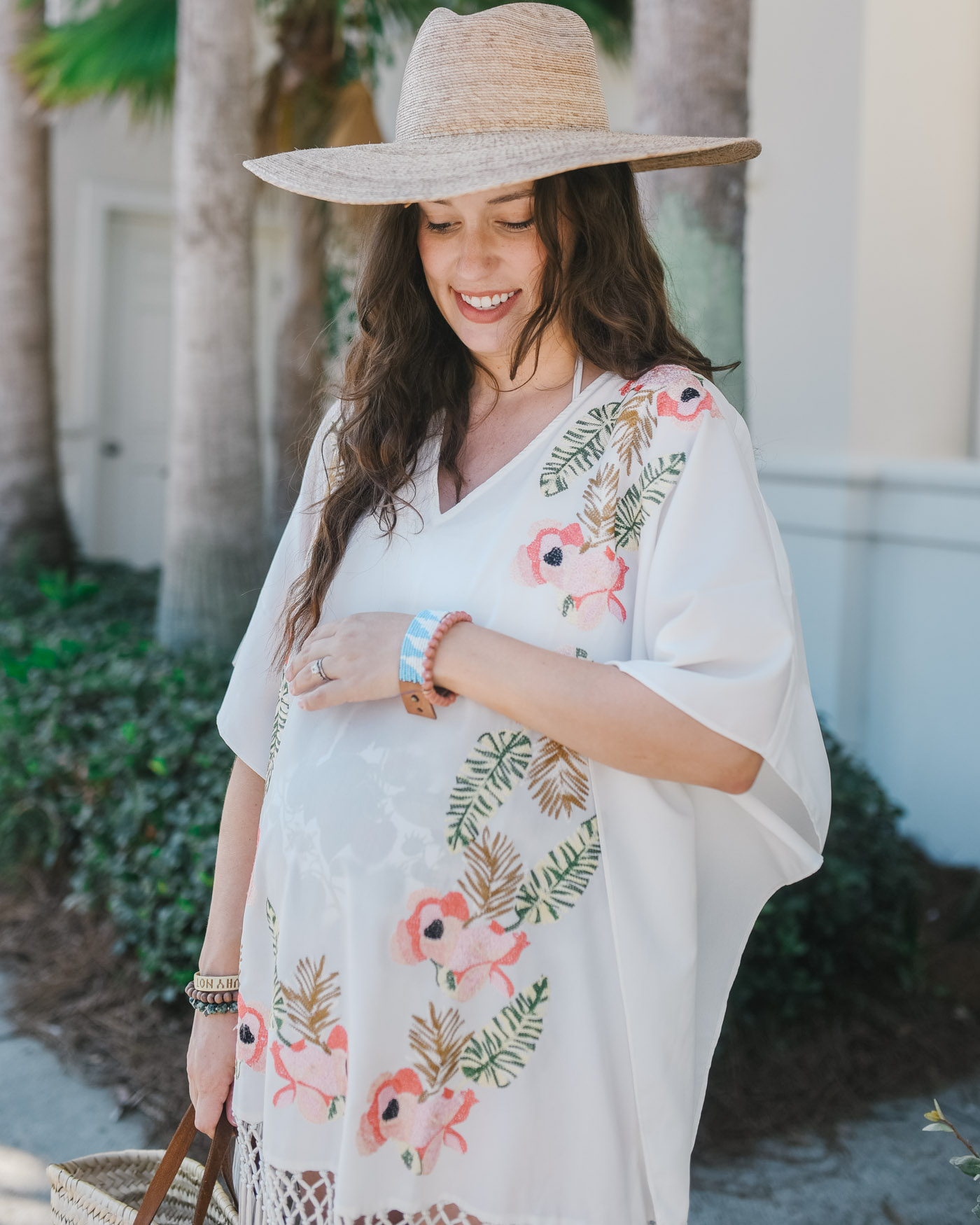  Maternity Style by popular Memphis fashion blog, Lone Star Looking Glass: image of a woman walking outside on a palm tree lined sidewalk while wearing a Show Me Your Mumu Maleia Tunic, Madwell WYETH™ Straw Ipanema Hat, ShopBop Soludos Braided Slide Sandals, and holding a Amazon Moroccan Straw Market Bag w/Blue Leather Strip Handles. 