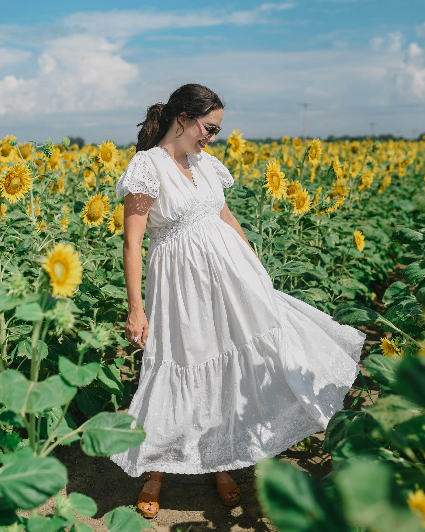 30 Weeks Pregnant by popular Memphis motherhood blog, Lone Star Looking Glass: image of a woman standing in a field of sunflowers and wearing a ChicWish FRILL HEM PLUNGING V-NECK SLEEVELESS MAXI DRESS IN WHITE, Swedish Hasbeens Kringlan, and Free People Western Cuff Set.