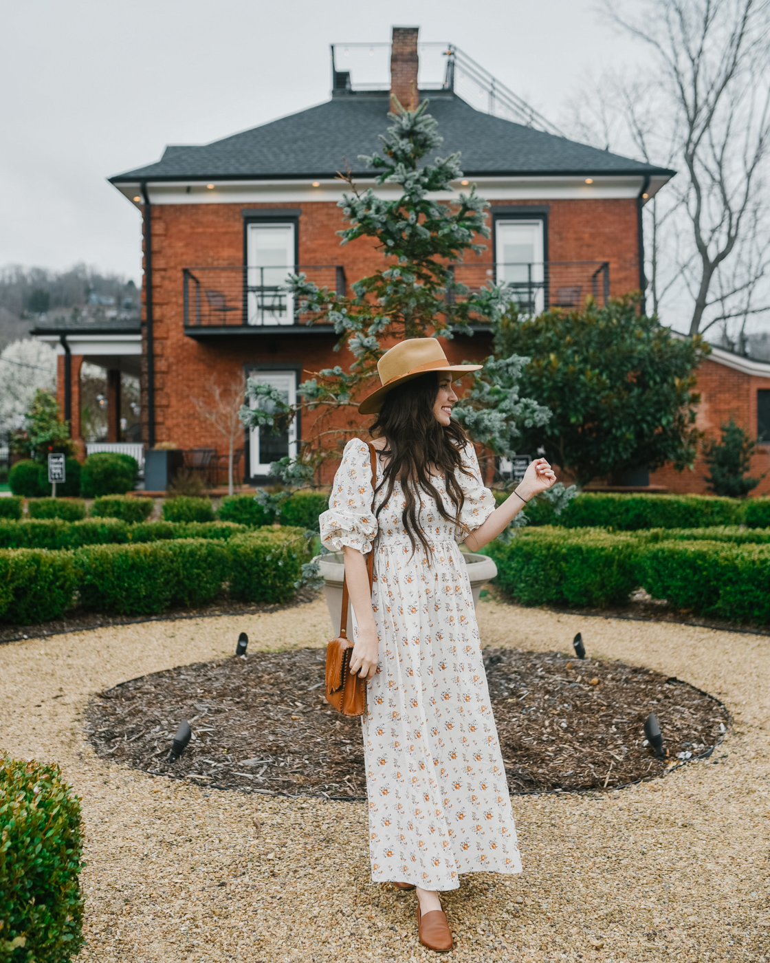 Bunn House by popular Memphis travel blog, Lone Star Looking Glass: image of a woman standing outside the Bunn House and wearing a Lack of Color hat and floral puff sleeve maxi dress. 
