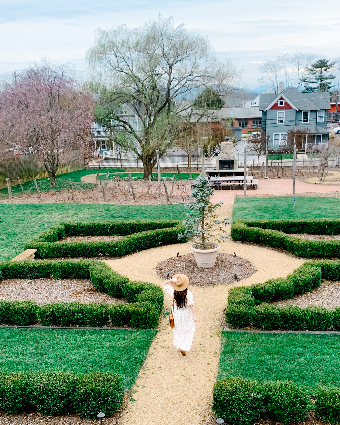 Bunn House by popular Memphis travel blog, Lone Star Looking Glass: image of a woman walking outside in the Bunn House grounds and wearing a Lack of Color hat and floral puff sleeve maxi dress. 