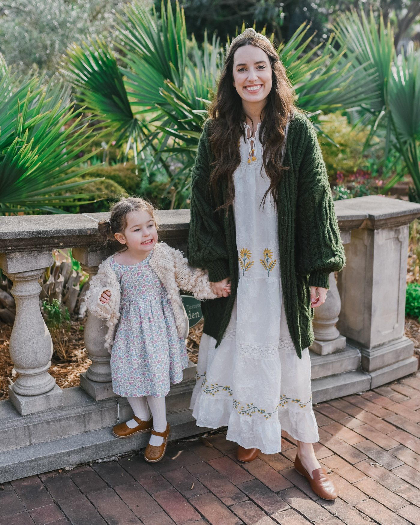 Things to do in Columbia SC by popular Memphis travel blog, Lone Star Looking Glass: image of a little girl wearing a pair of Maisonette Joy Vintage Inspired Stitch Down T-Strap Mary Jane, Spicy Mustard and a ChichWish KNIT YOUR LOVE CARDIGAN IN IVORY FOR KIDS and holding her mom's hand. 