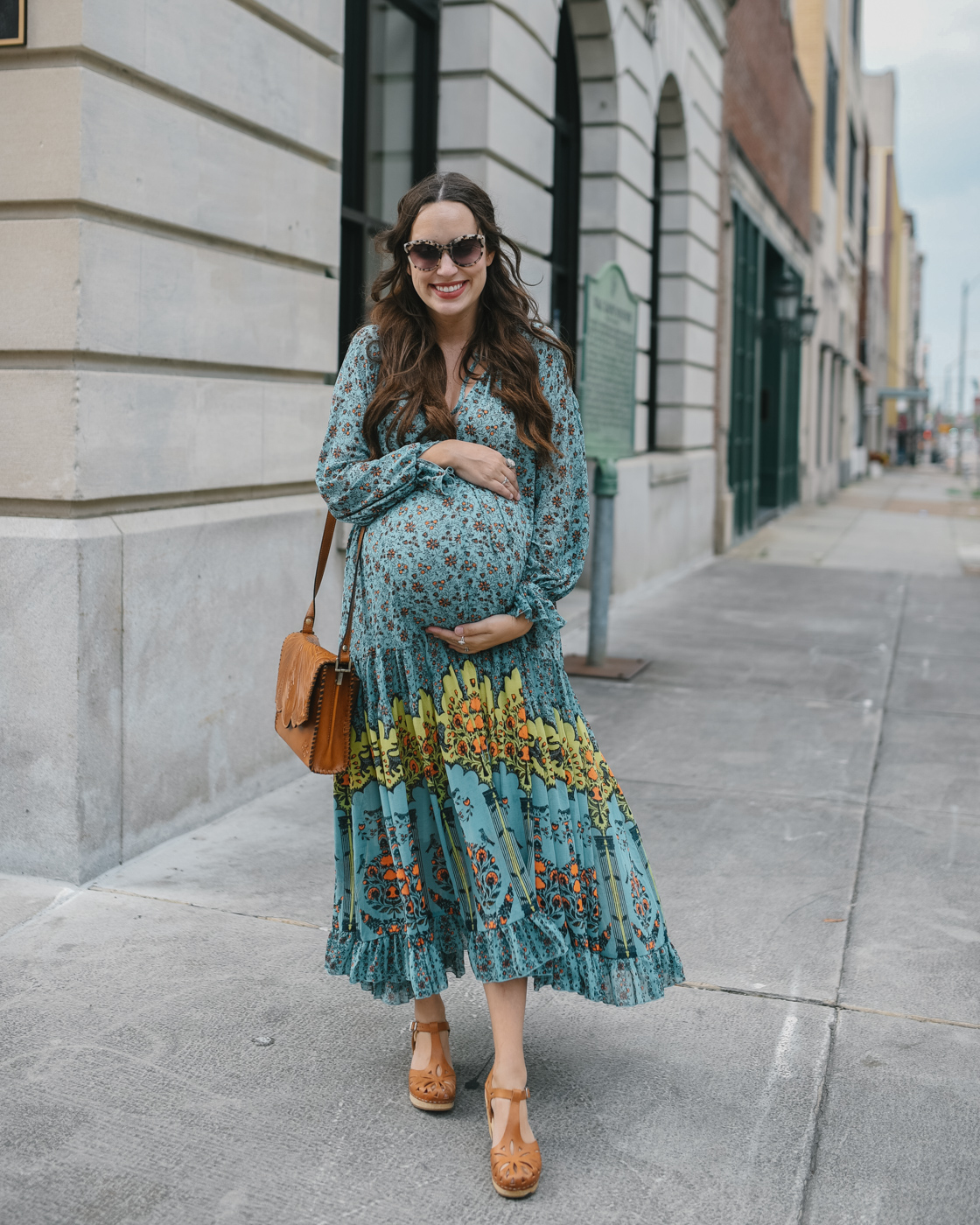 Fall Clothing by popular Memphis fashion blog, Lone Star Looking Glass: image of a woman walking down a city sidewalk and wearing a Free People Free People Feeling Groovy Border Printed Maxi Dress, Swedish clogs, and carrying a Patricia Nash Leather Sarola Crossbody.