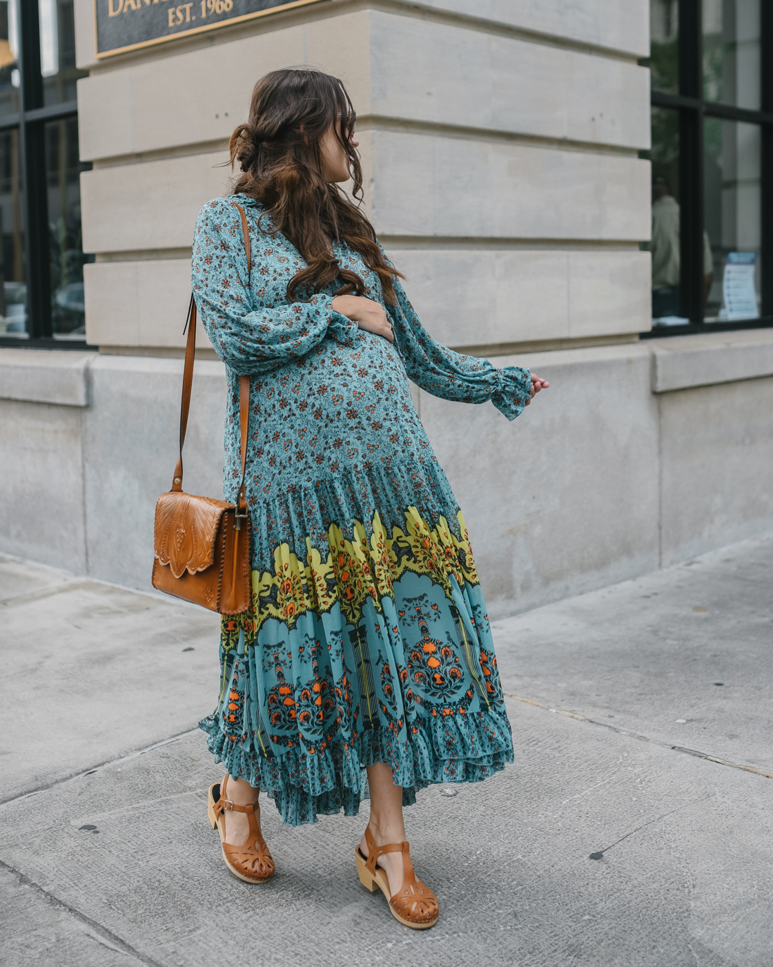 Fall Clothing by popular Memphis fashion blog, Lone Star Looking Glass: image of a woman walking down a city sidewalk and wearing a Free People Free People Feeling Groovy Border Printed Maxi Dress, Swedish clogs, and carrying a Patricia Nash Leather Sarola Crossbody.