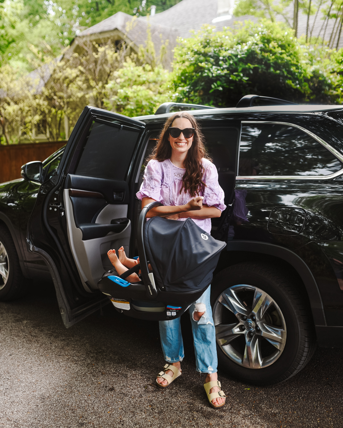 Maxi Cosi Coral XP Car Seat by popular Memphis motherhood blog, Lone Star Looking Glass: image of a mom standing next to a black car and holding her young son in a Maxi Cosi Coral XP car seat. 