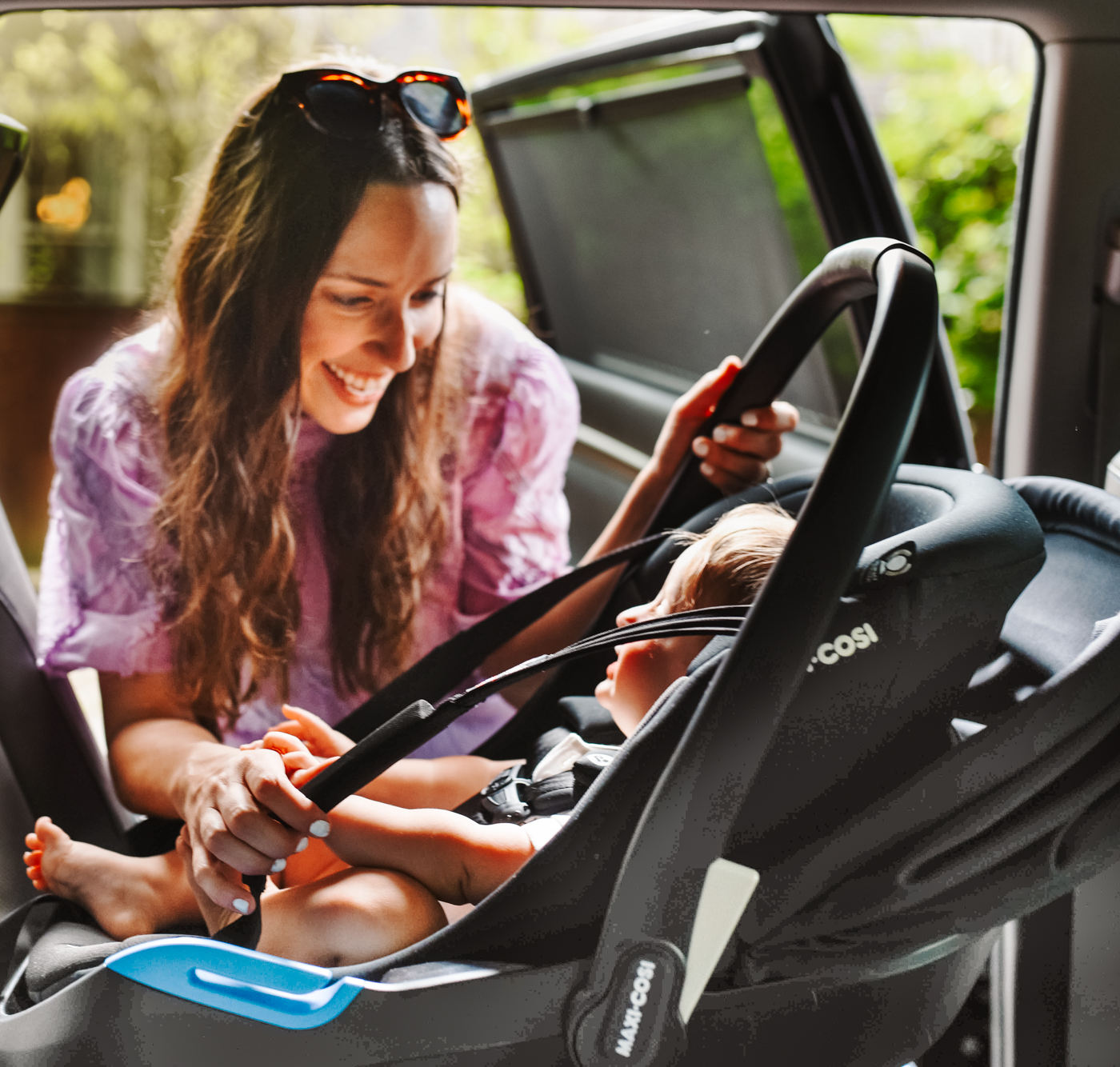 Maxi Cosi Coral XP Car Seat by popular Memphis motherhood blog, Lone Star Looking Glass: image of a mom putting a Maxi Cosi Coral XP car seat with her son in it, in her car. 