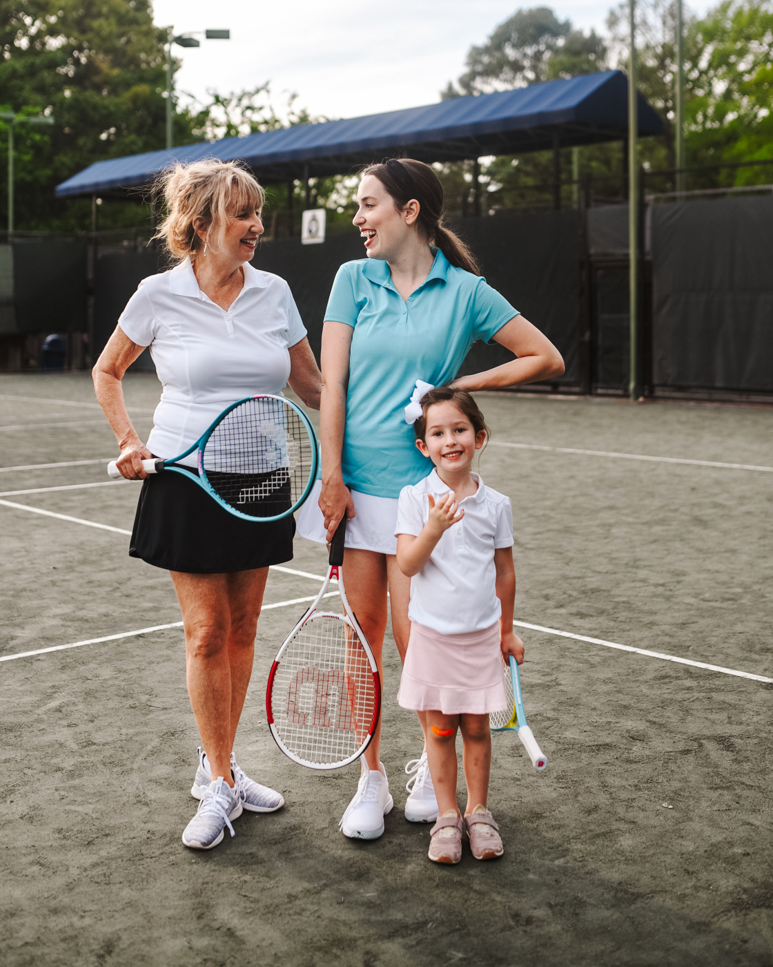 Tennis Outfits by popular Memphis fashion blog, Lone Star Looking Glass: image of three women standing together on a tennis court and holding tennis rackets and wearing tennis outfits. 