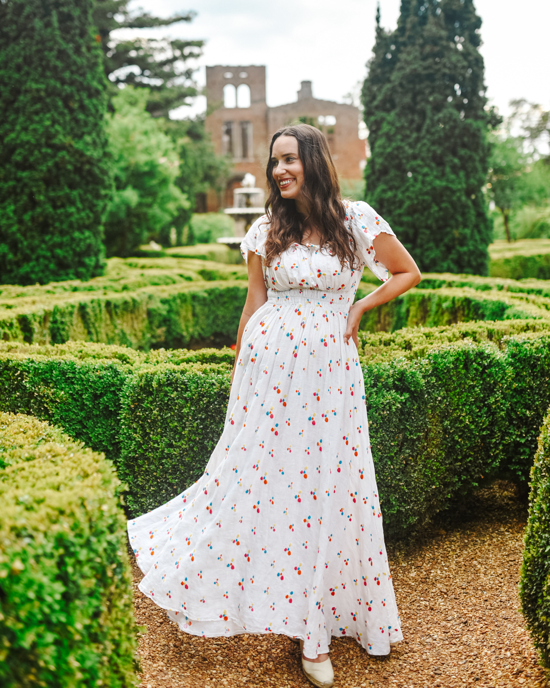 Barnsley Resort by popular Memphis travel blog, Lone Star Looking Glass: image of a woman standing in a hedge maze and wearing a white and red print floral maxi dress. 