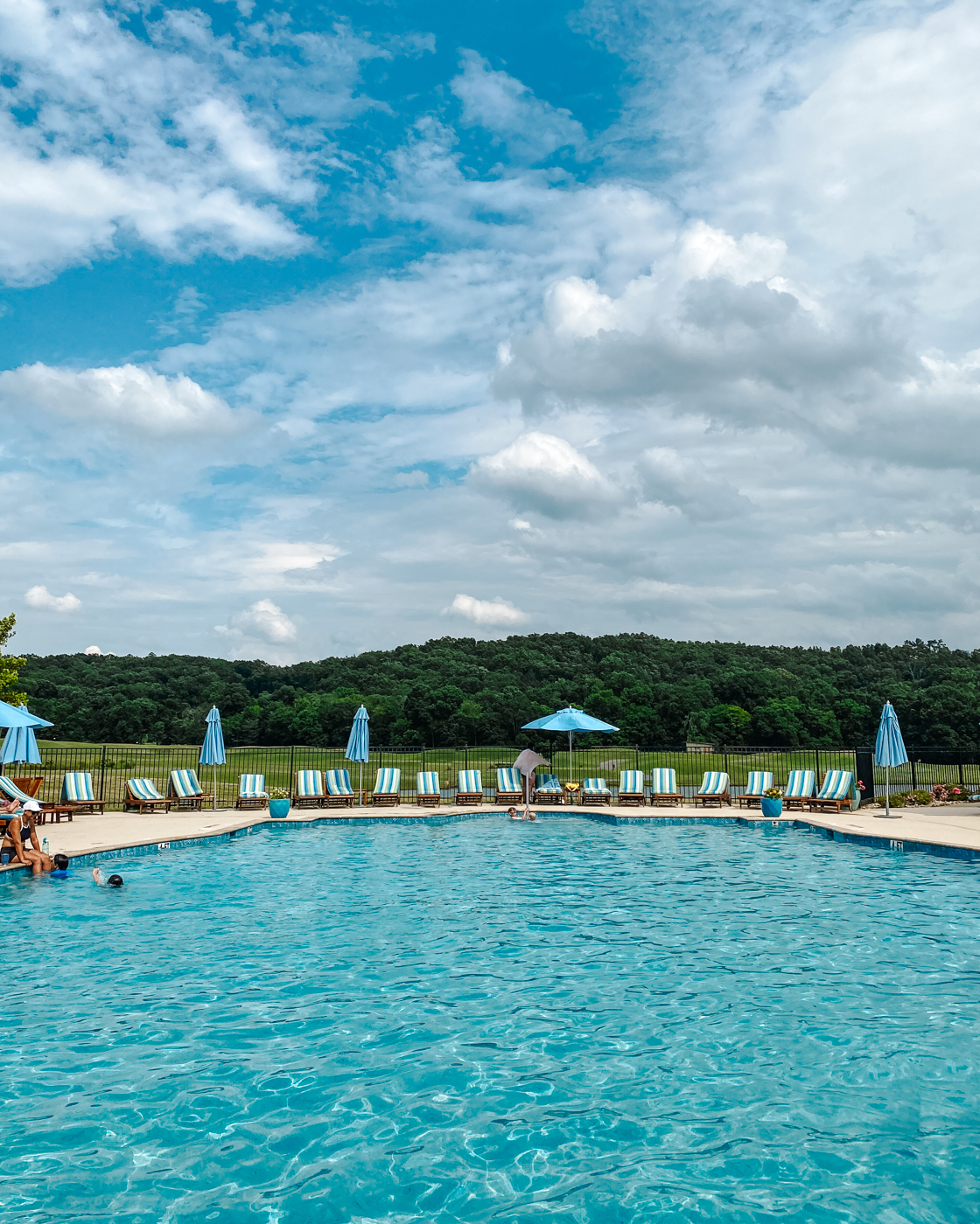 Barnsley Resort by popular Memphis travel blog, Lone Star Looking Glass: image of a swimming pool with blue shade umbrellas and blue and white stripe lounge chairs. 