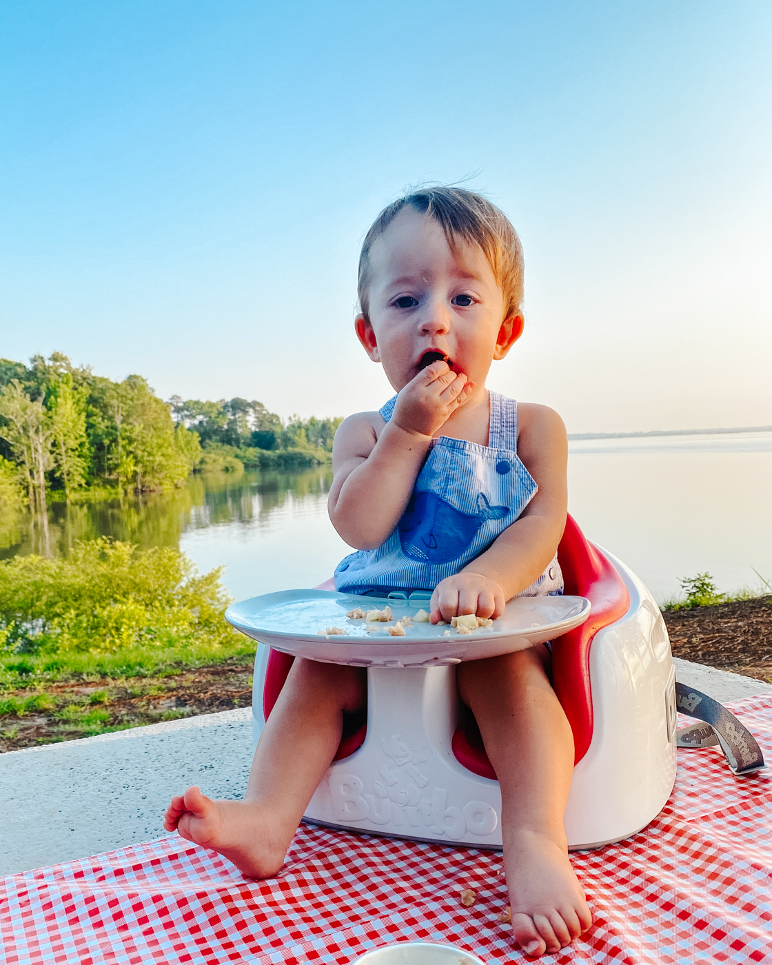 Camping With Kids by popular Memphis lifestyle blog, Lone Star Looking Glass: image of a little boy sitting in a Bumbo chair and eating food off of a tray. 