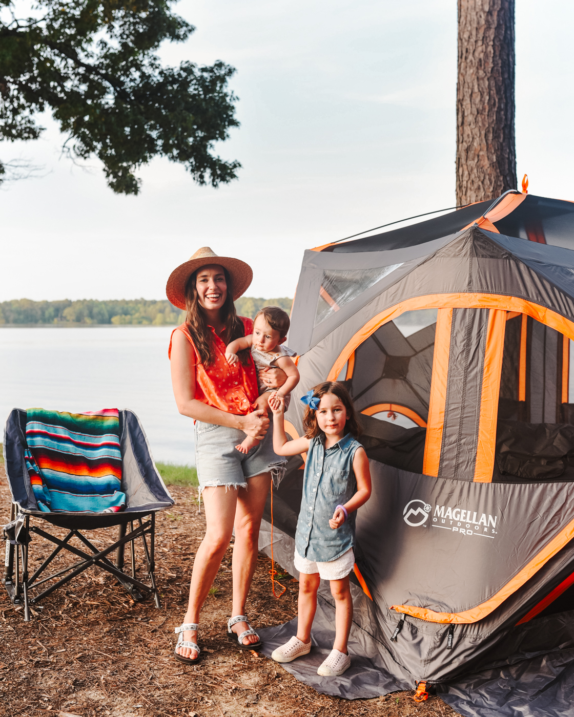Camping With Kids by popular Memphis lifestyle blog, Lone Star Looking Glass: image of a mom and her young son and daughter standing next to a camping chair and their Magellan tent. 