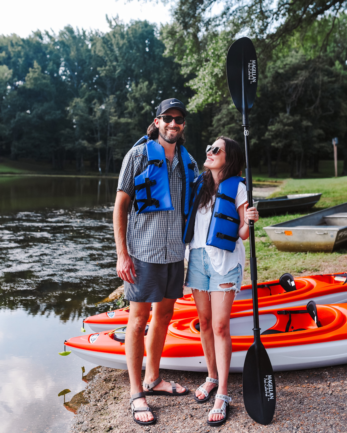 Kayaking for Beginners by poplar Memphis lifestyle blog, Lone Star Looking Glass: image of a husband and wife wearing blue life jackets and standing next to some red kayaks. 