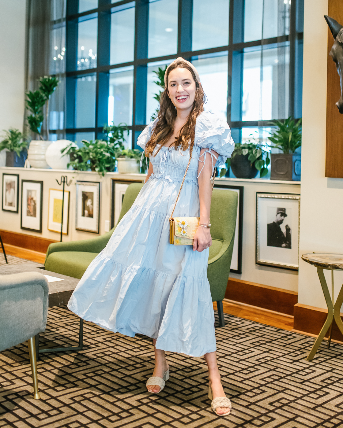 Prairie Dress by popular Memphis fashion blog, Lone Star Looking Glass: image of a woman wearing a blue puff sleeve prairie dress with a tan knot headband, and tan braided strap block heel mules. 