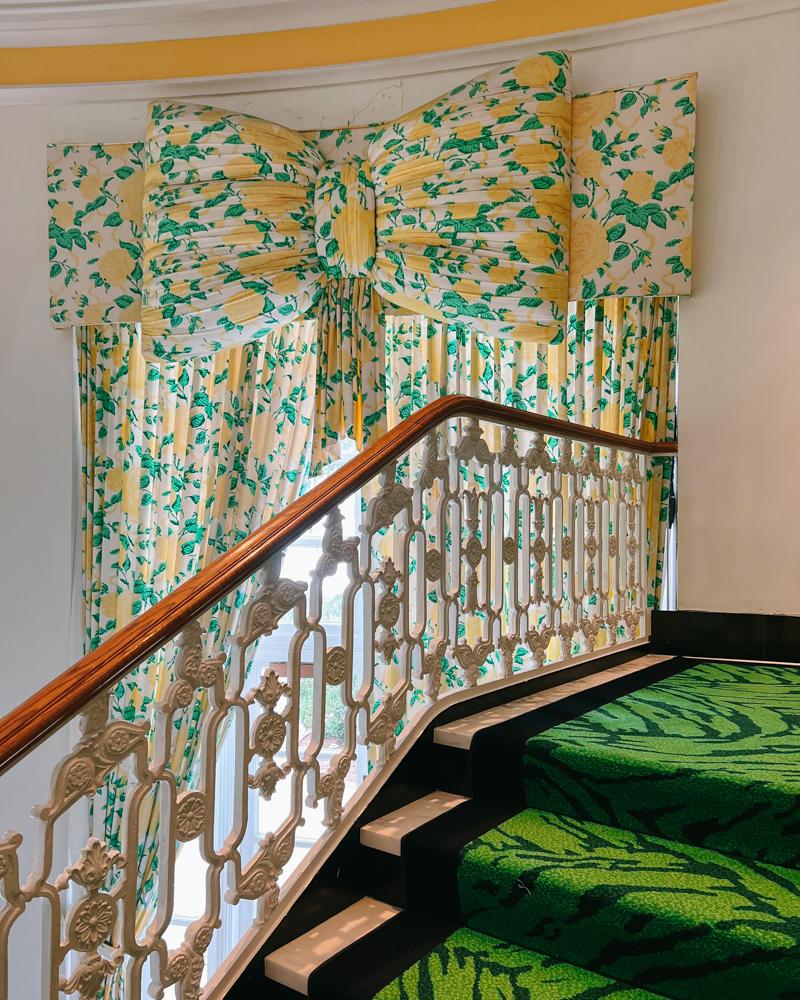 “Lemon-yellow Dorothy Draper bow draperies at The Greenbrier’s grand staircase — cheerful Southern glamour at its finest